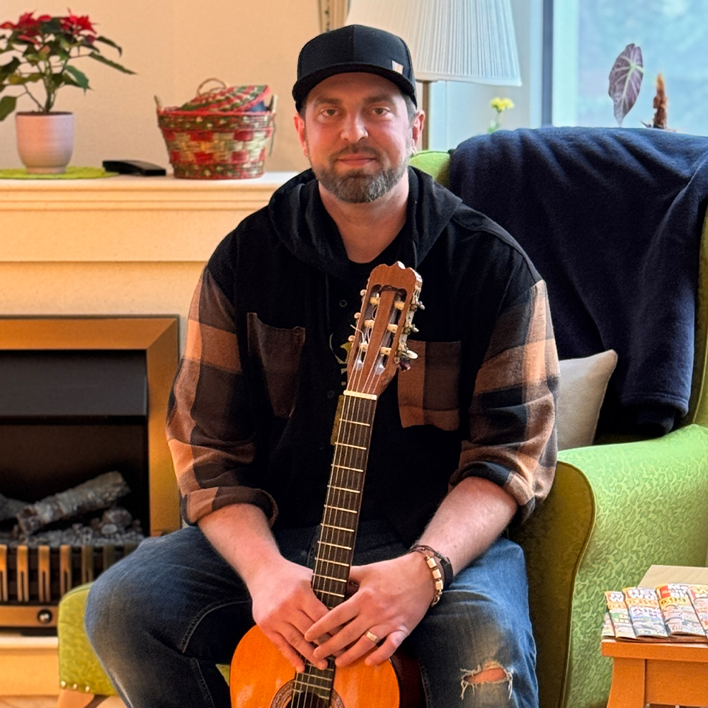 Schwalm Care - Tagespflege - Nahaufnahme von Mitarbeiter, die eine akustische Gitarre im Sitzen spielt